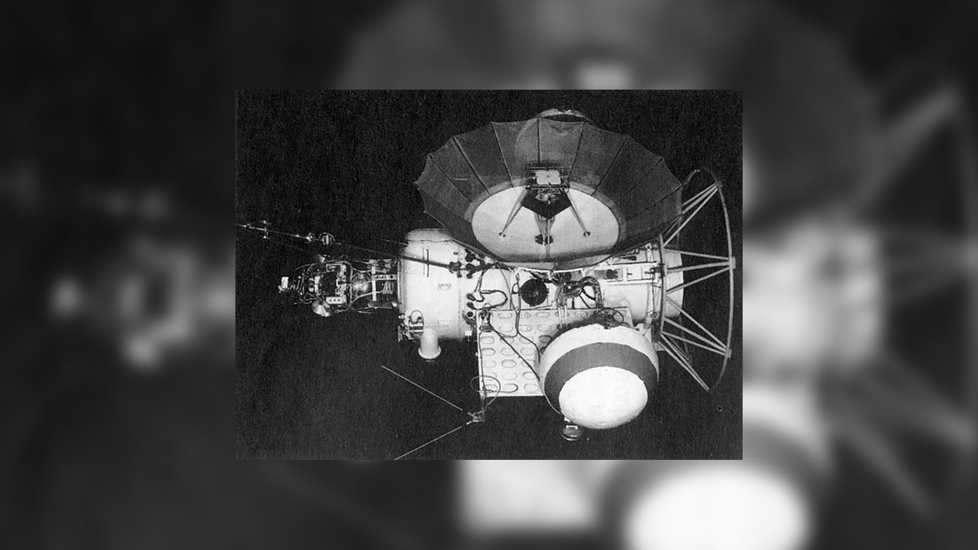 a black and white photo of a white spacecraft with a large radio dish on one side