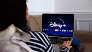 A woman on a laptop with the Disney logo.