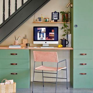 Home office area with green cabinetry built in under stair space