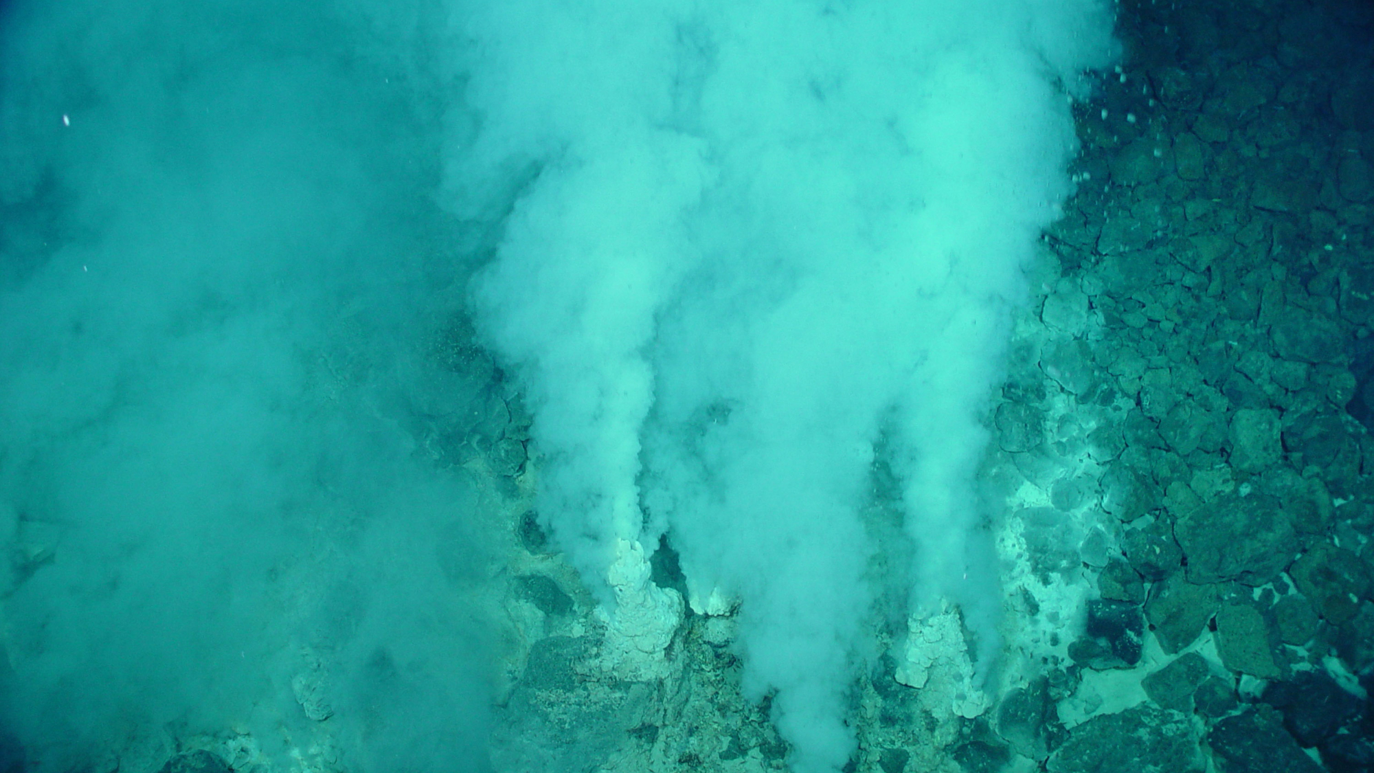 A deep-sea vent in the Marianas region on Earth with gas rushing out from the sea floor.