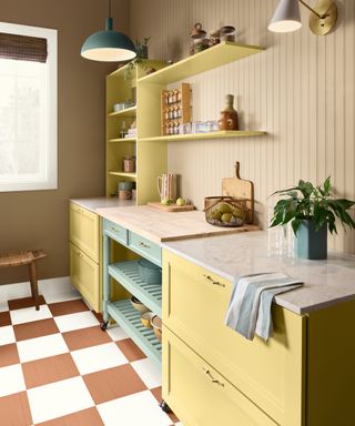 kitchen with yellow cabinets, beige panelled walls and brown and white checked floor