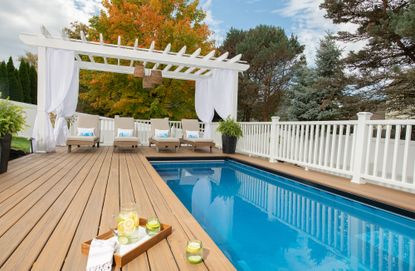 above ground pool with a wooden deck and lounge seating