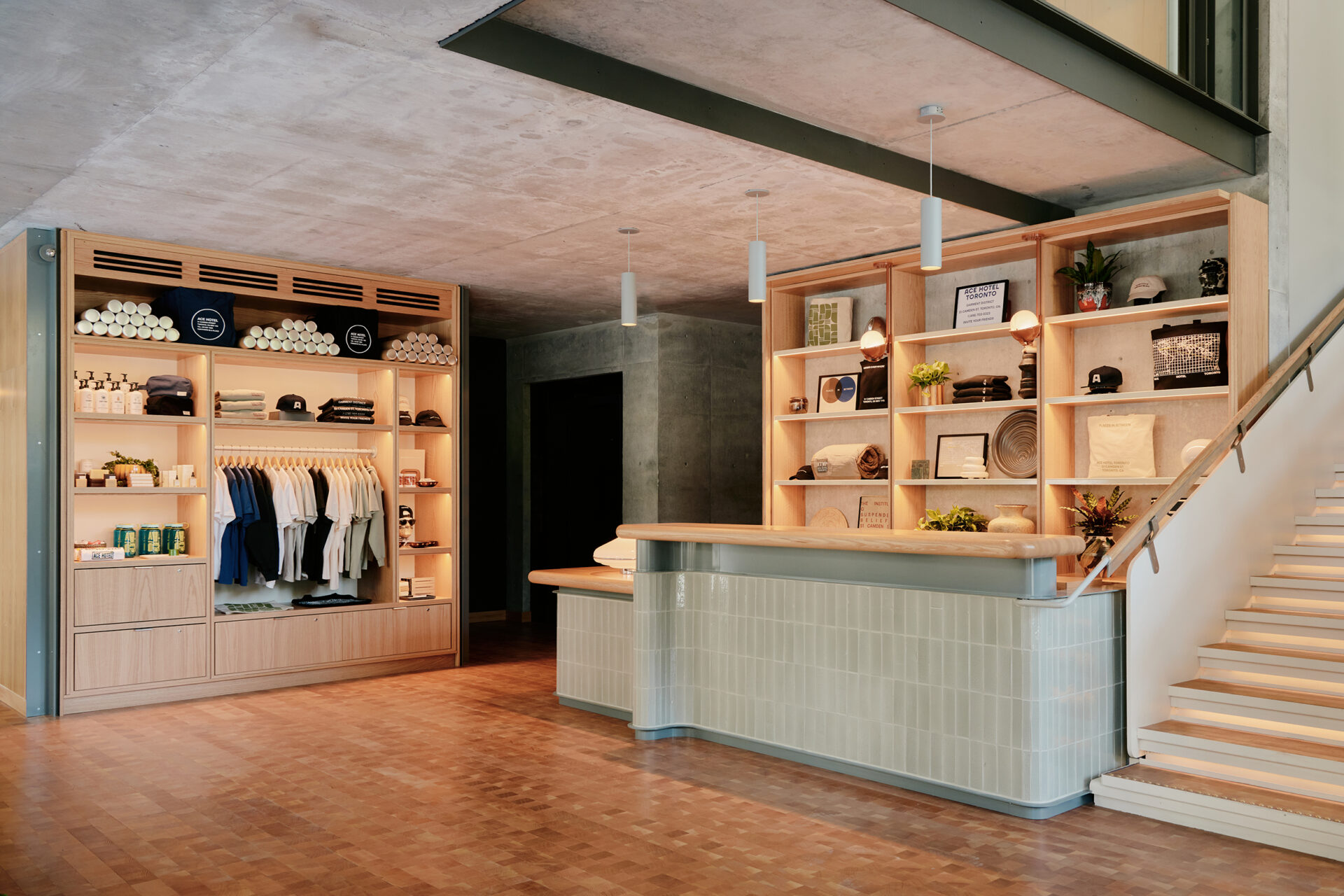 A record shop-inspired hotel gift shop features water green tiles, pale wooden surfaces, and collectibles in a dimly lit, cool atmosphere.