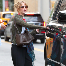 Image of Jennifer Lawrence today wearing a the leopard print mules trend 2026. She paired with with an olive cardigan, white T-shirt and black trousers. 