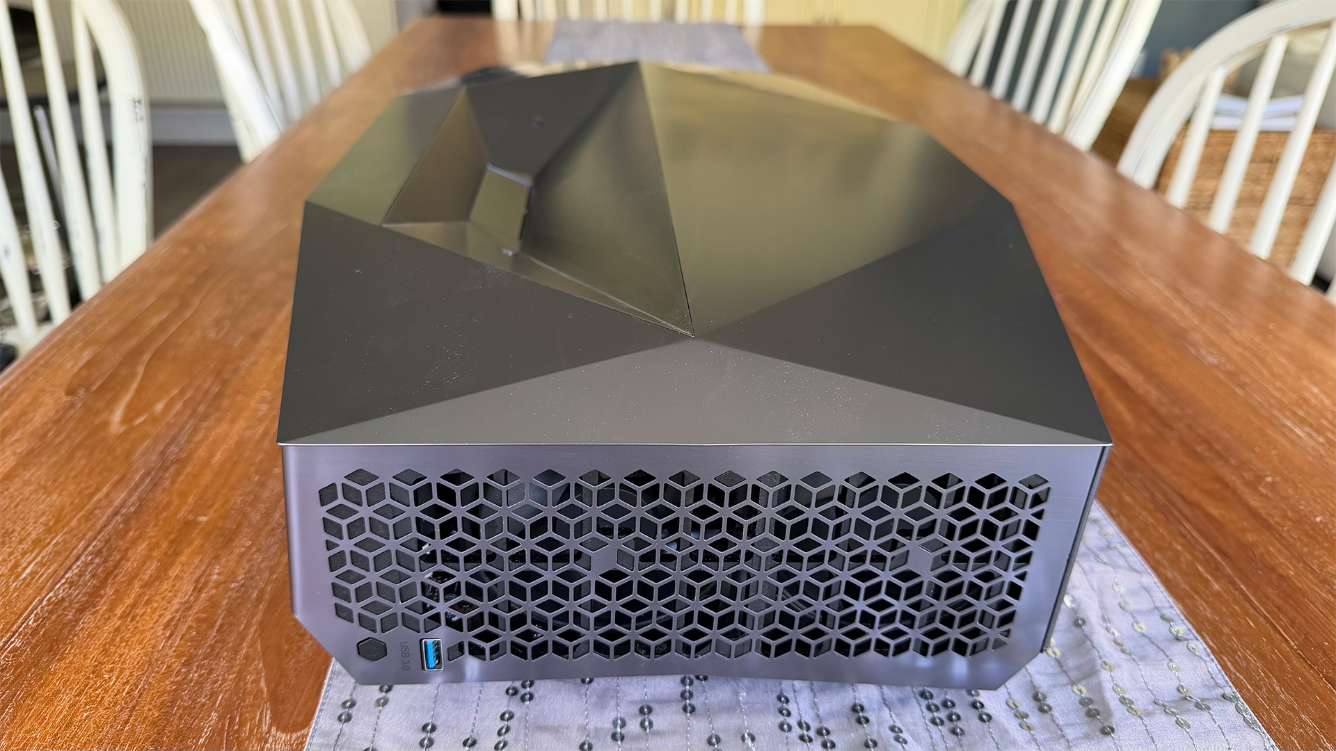 AWOL Vision Aetherion Max ultra short throw projector on wooden dining table view from side and slight elevation