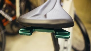 A green aluminium saddlebag mount under a saddle
