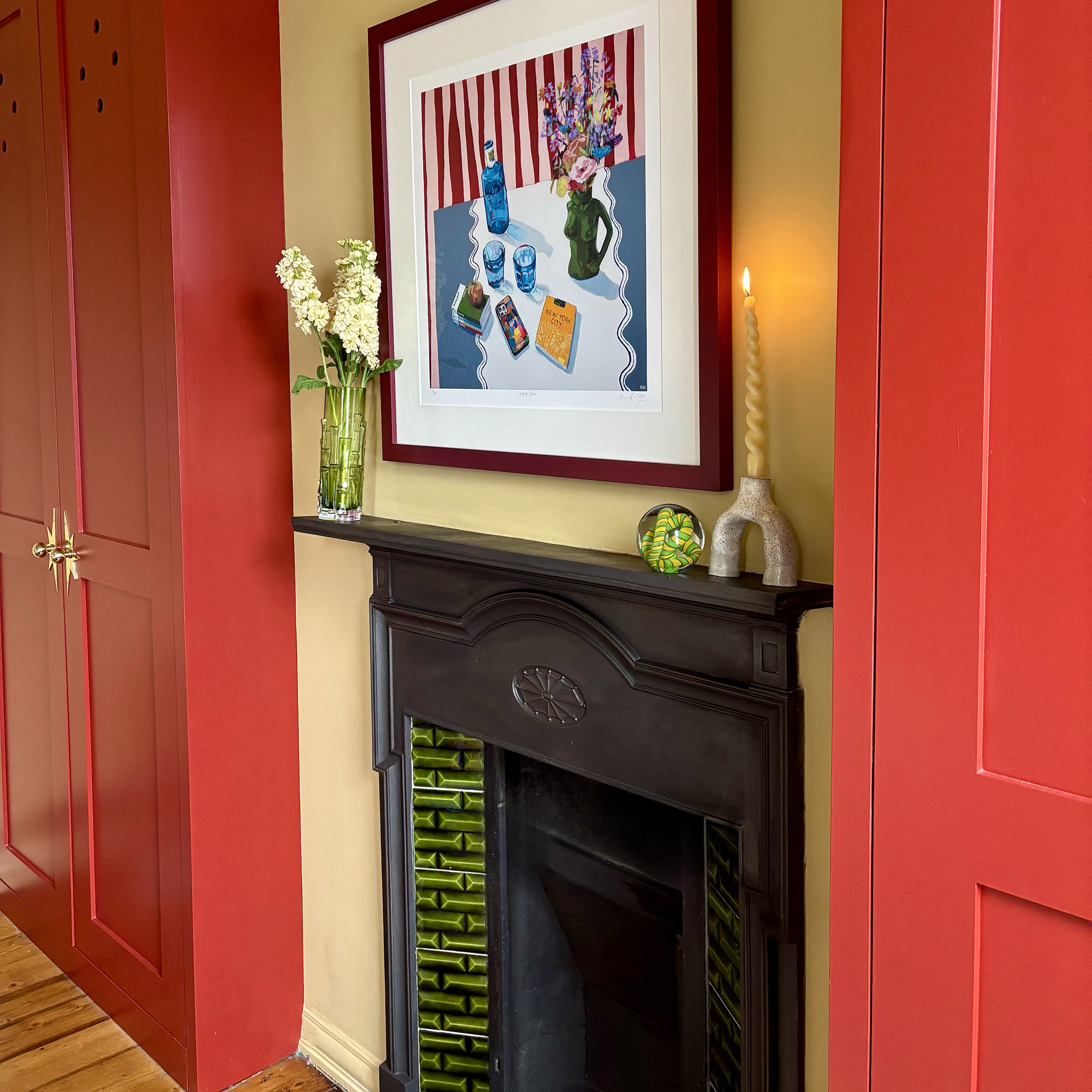 fireplace between red joinery with candlestick, ornaments and a vase on it