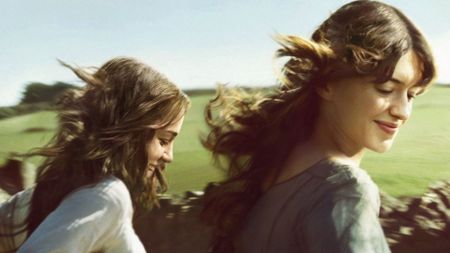 Two girls run through a field
