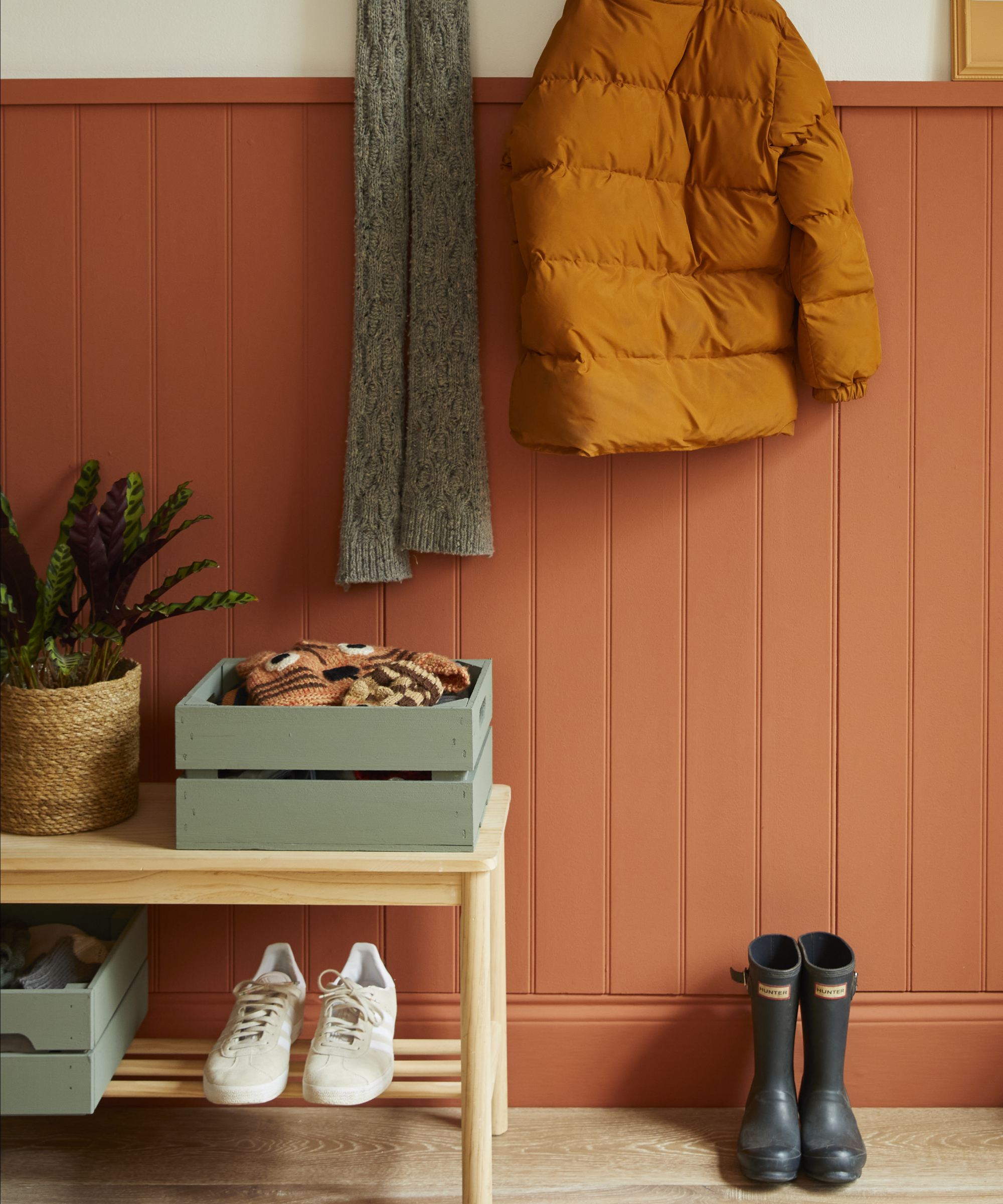 orange painted half height tongue and groove wall panelling with light wooden shoe storage bench