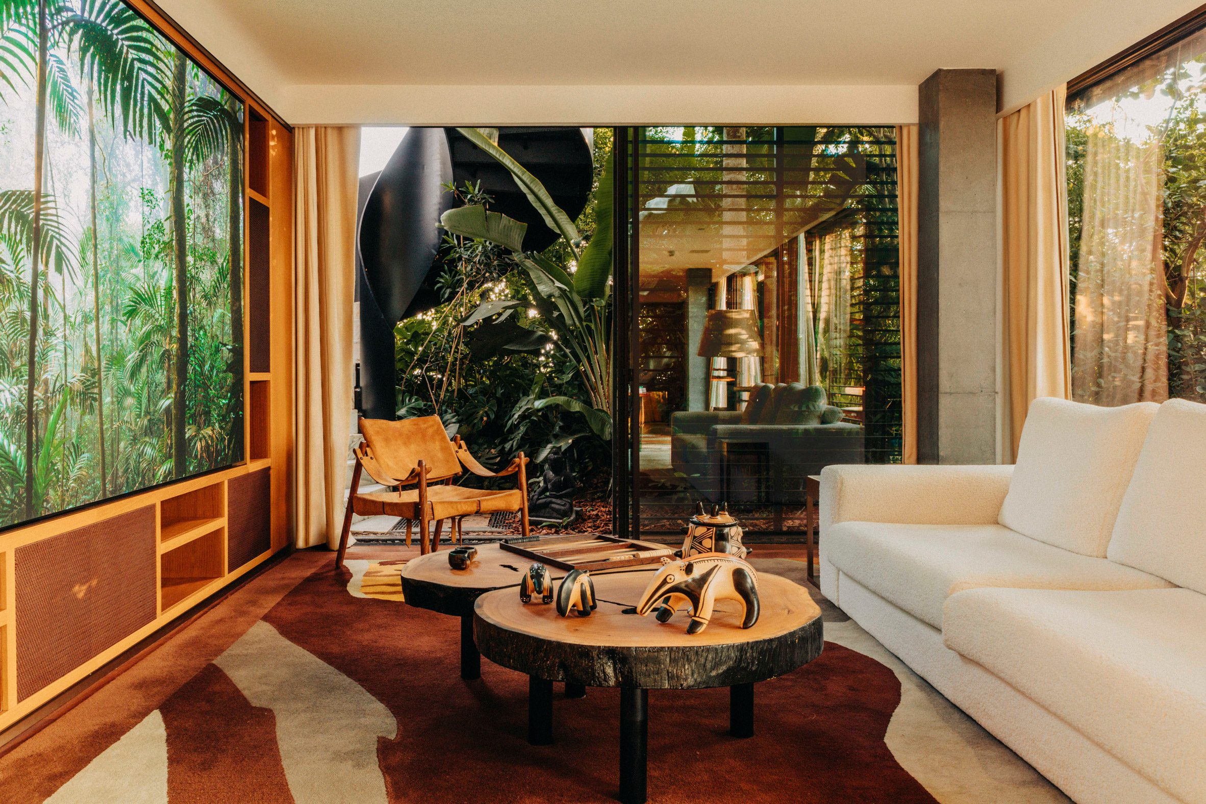 A spectacular, sun-filled penthouse blends Brazilian heritage with sleek surfaces, sculptural furniture, and researched artwork, also incorporating greenery into an earthy scheme.