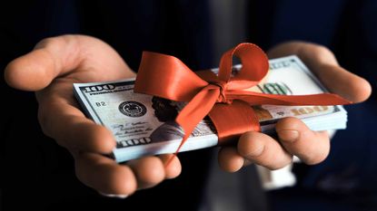 person giving money wrapped in red bow