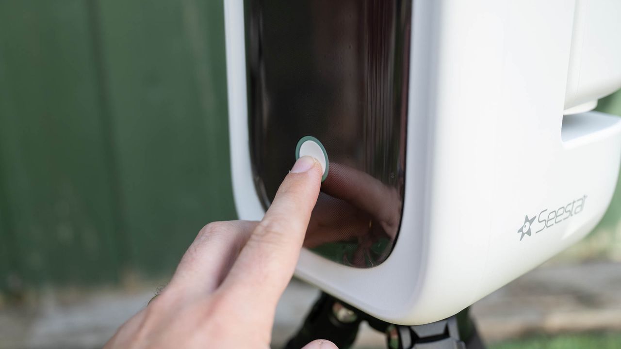 Someone pressing the power button on the ZWO Seestar S50 Pro