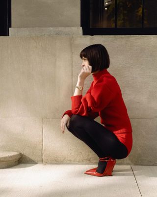 Woman wearing red wedges and a turtleneck.