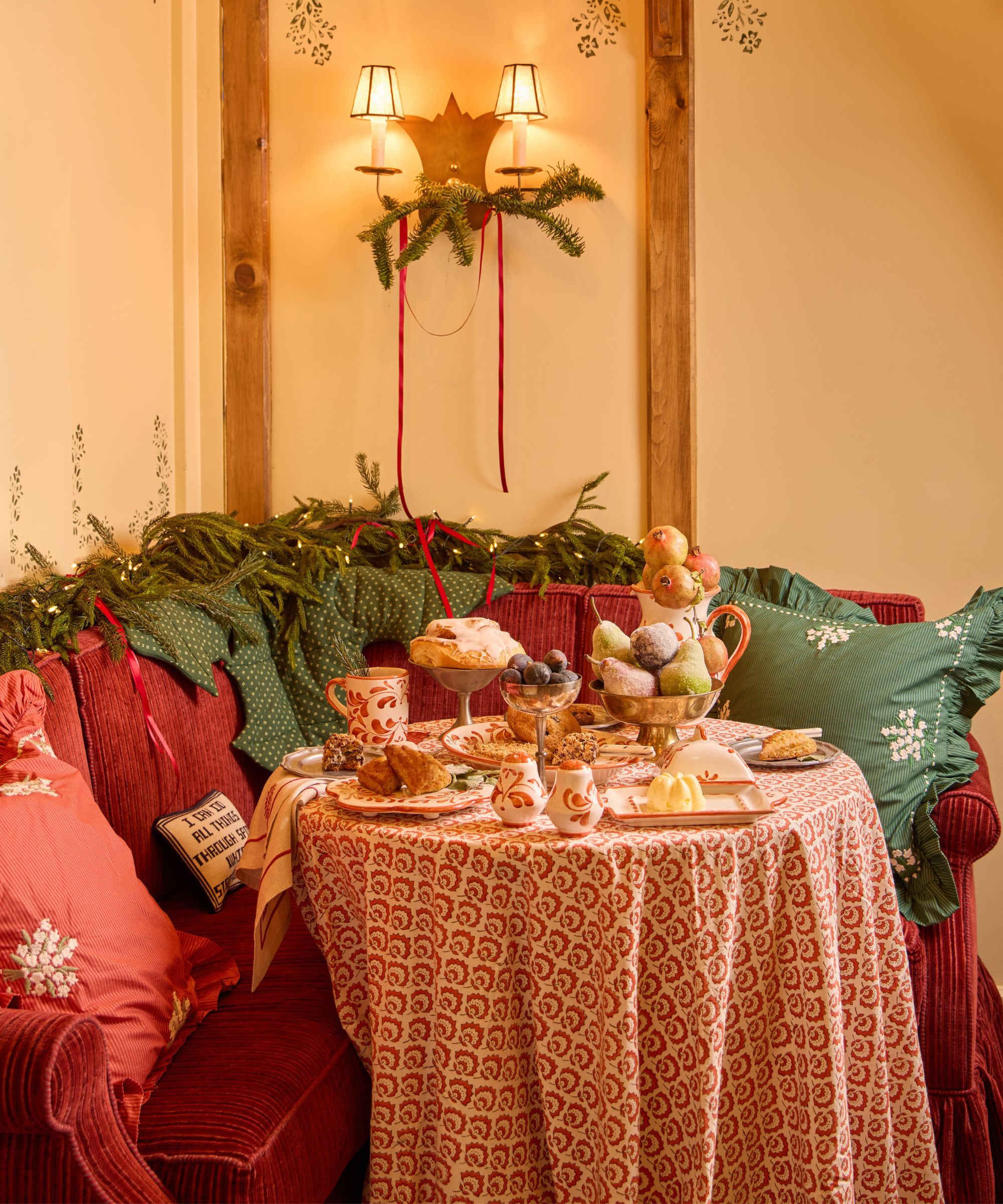 a small banquette seat and tabe styled fro christmas breakfast with garlands, red and green decor and handpainted tableware