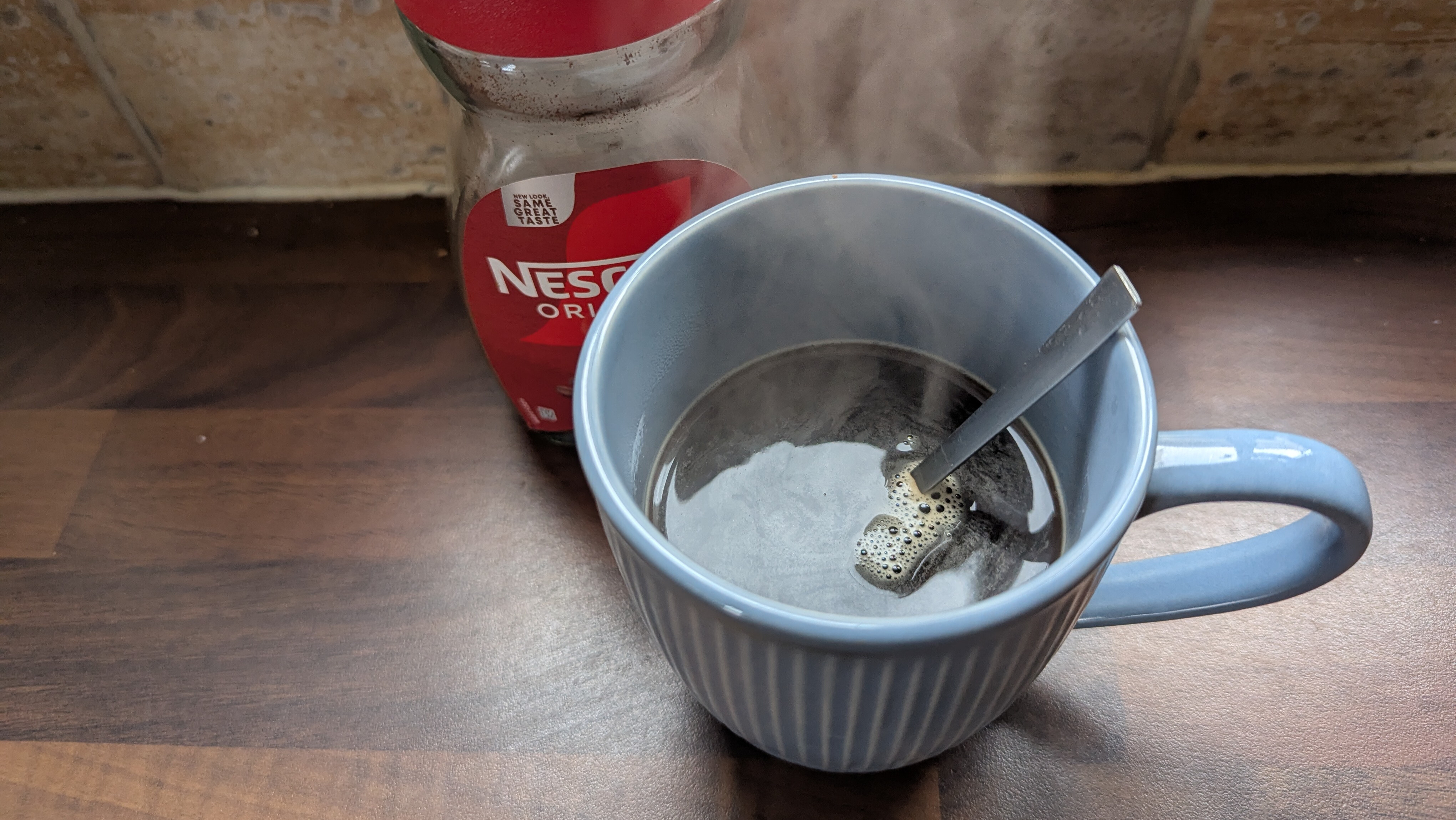 A steaming cup of coffee on the table with a red capped bottle next to it as our Tom's Guide sleep writer prepares for a coffee nap