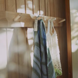 A wood panelled wall with patterned towels hanging from pegs
