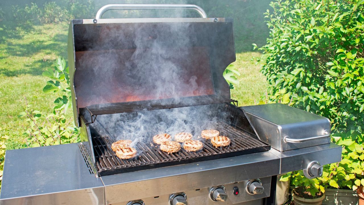 Grilling burgers on a gas grill and causing grill smoke