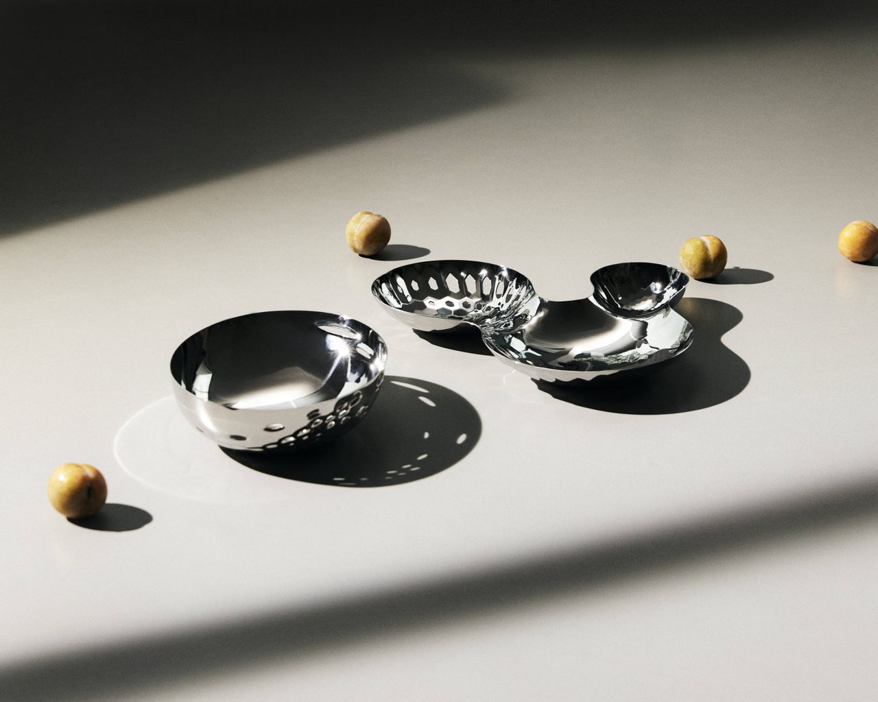 Zaha Hadid Design Tableware: stainless steel, perforated, rounded bowls on white surface