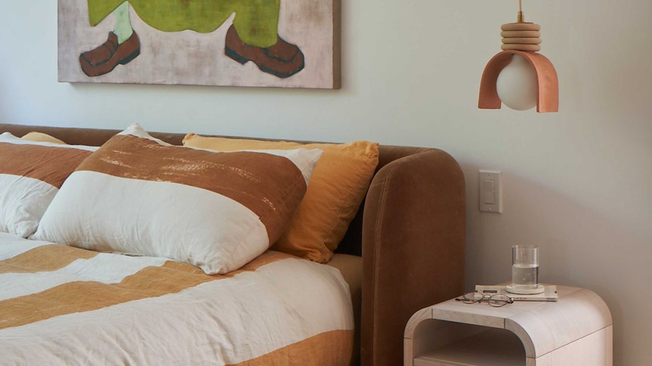 a rust colored bed with striped linen