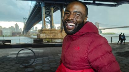 Best down jacket: Pictured here, a smiling model wearing The North Face Thermoball 50/50 Jacket under a bridge