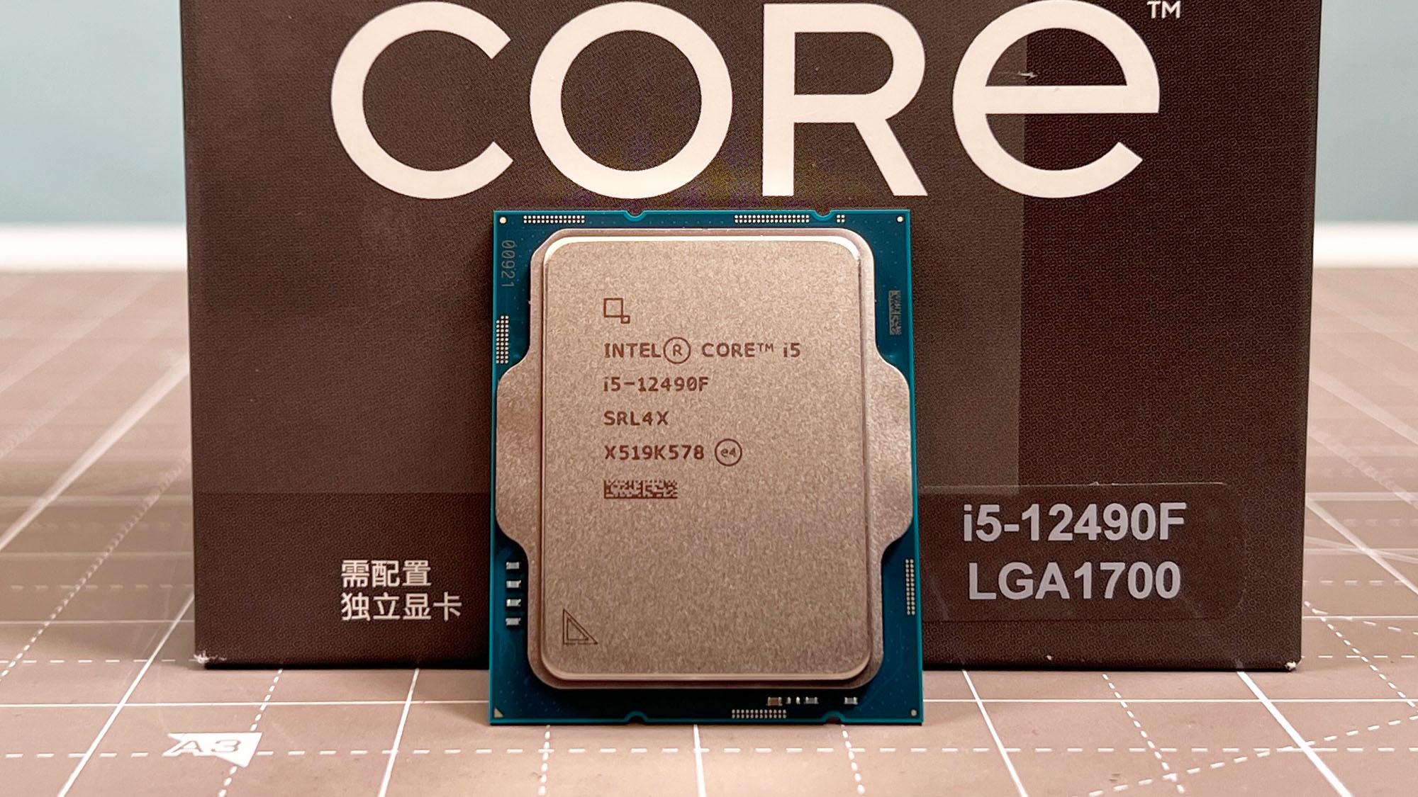An Intel Core i5-12490F standing upright on a desk in front of its retail packaging