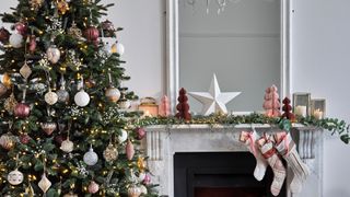 Christmas tree next to mantelpiece decorate with blush pink decorations