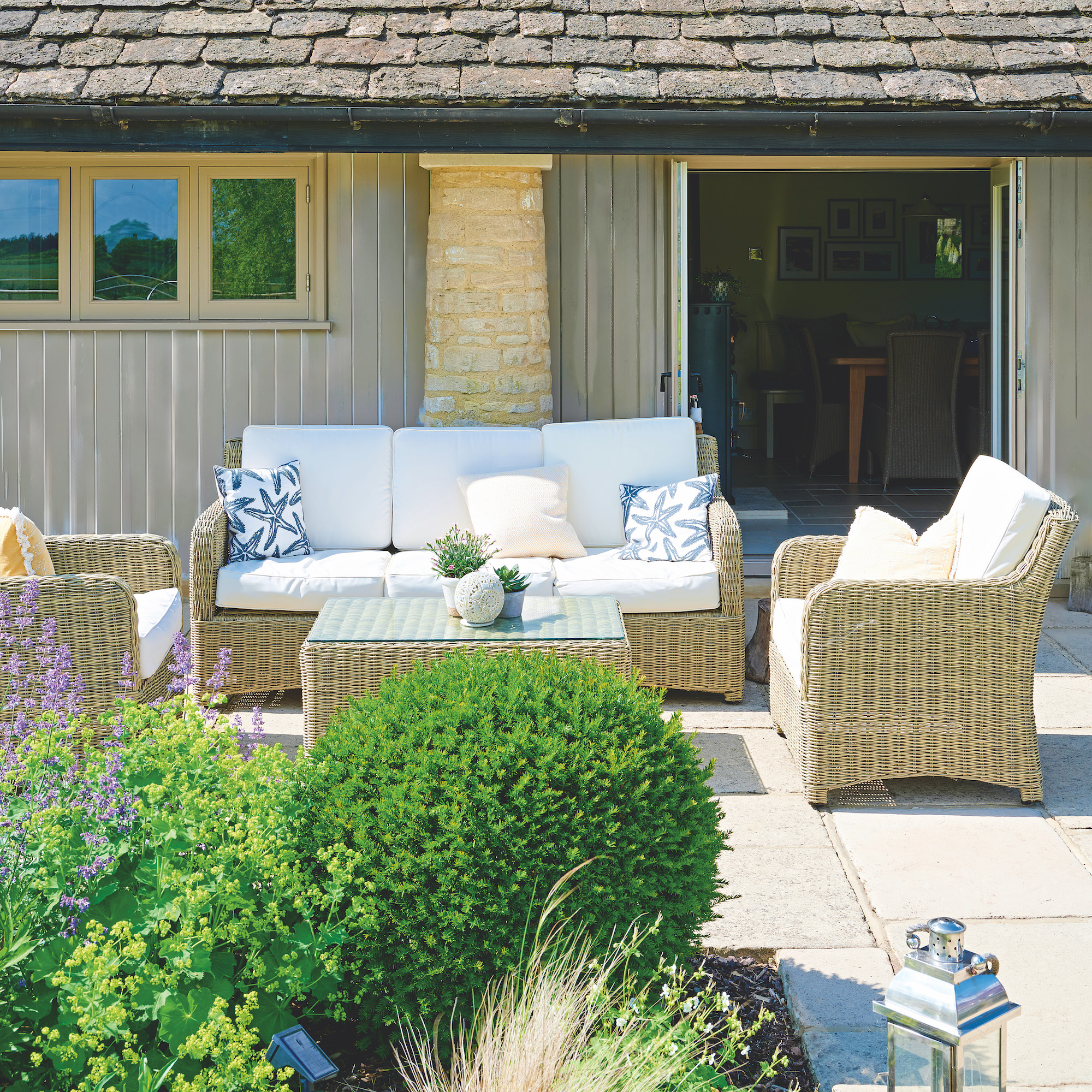 exterior of converted cowshed with patio with wicker patio furniture