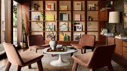 A mid-century modern library with four chairs and a wall of display books