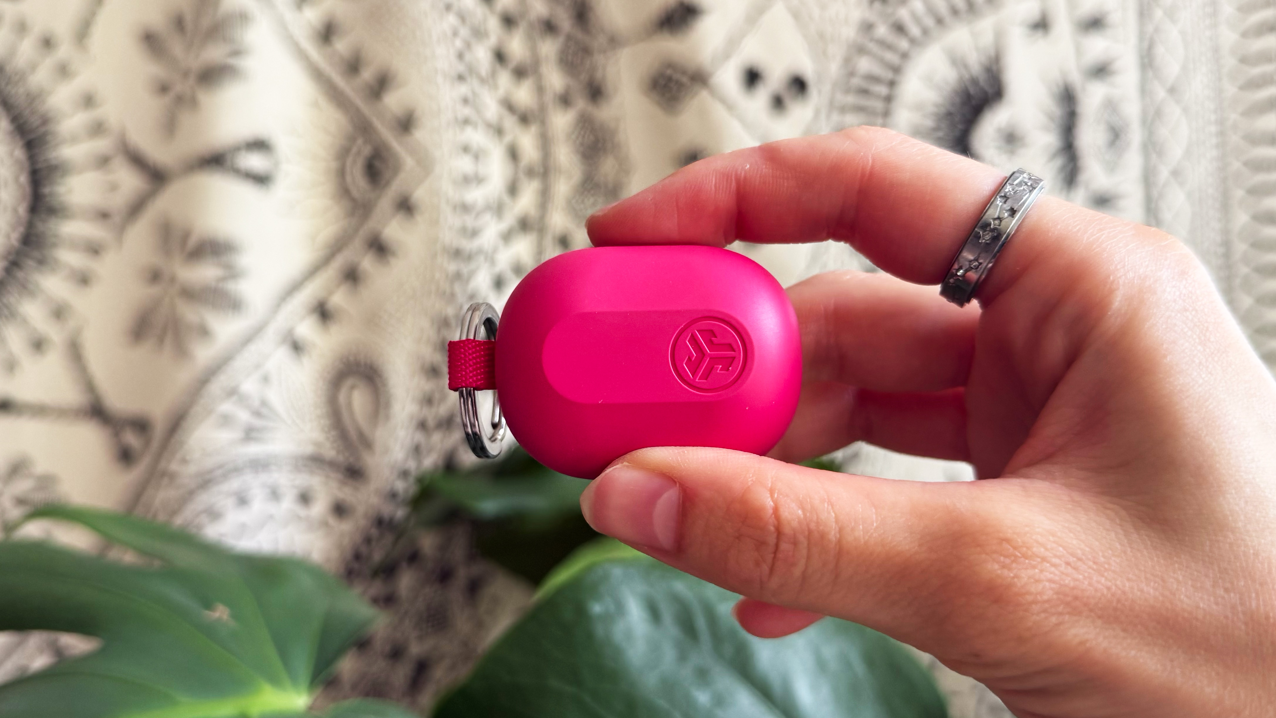 the jlab jbuds mini earbuds charging case held between the thumb and index finger showing miniature size