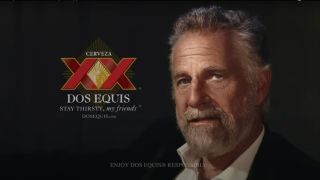 Jonathan Goldsmith sits stoically next to the logo for Dos Equis.