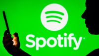 Woman holding a phone with Spotify logo in background