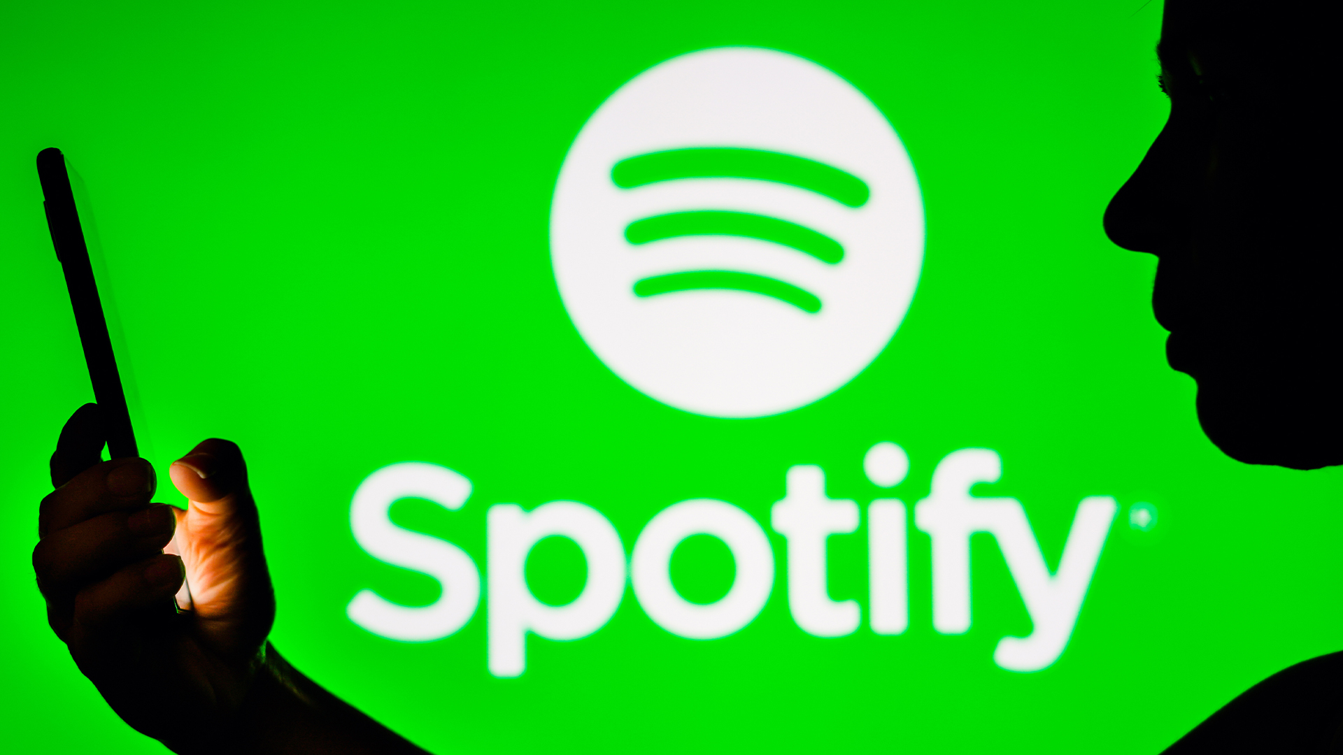 Woman holding a phone with Spotify logo in background