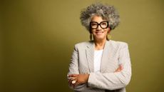 Senior businesswoman posing with her arms crossed against green studio background.
