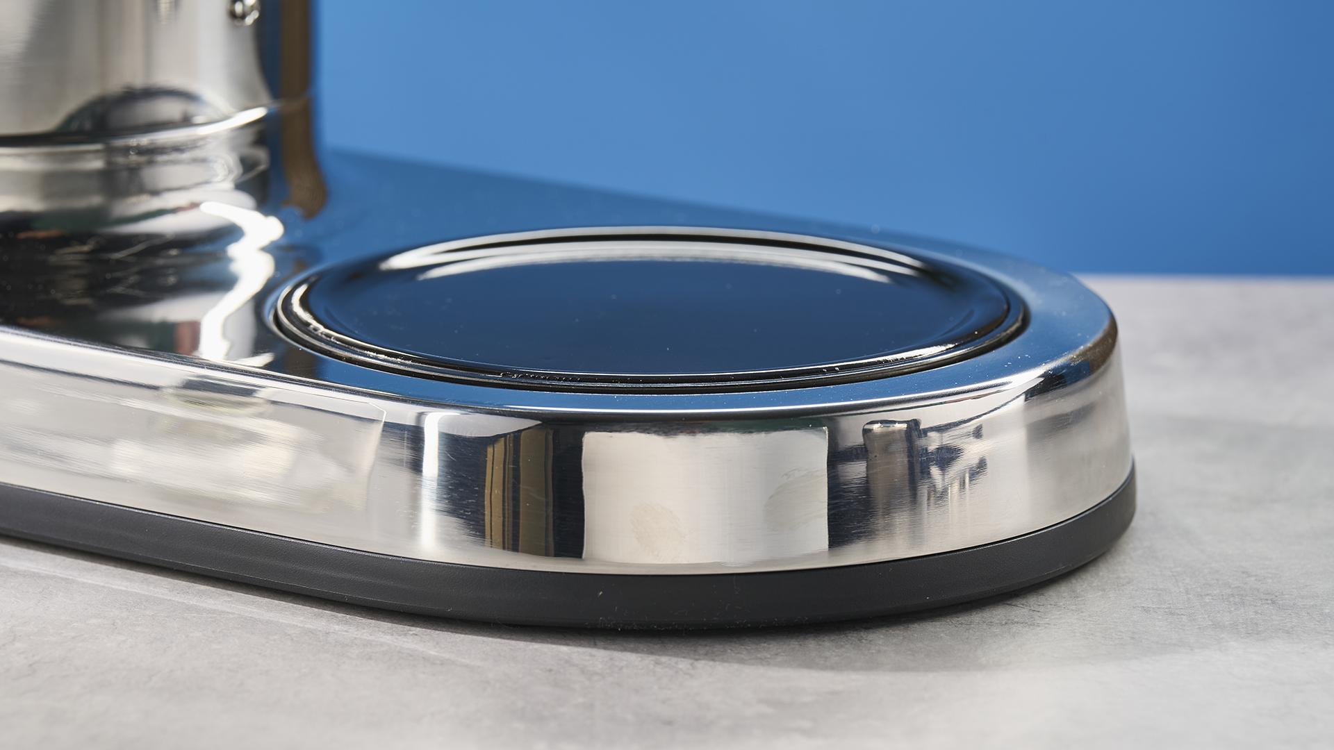 the heating plate of a silver drip coffee maker with a capacity of 10 cups is photographed against a blue background