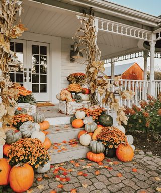 Cozy White Cottage Seasons porch with dried garlands, flowers and fall leaves - Cozy White Cottage Seasons