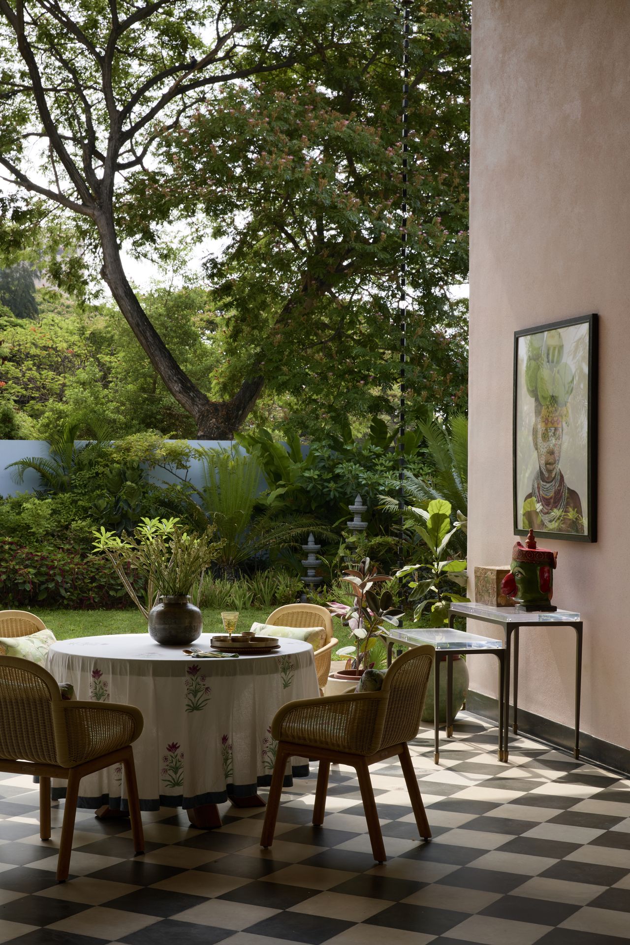An outdoor space with chequerboard flooring, seating, a dining table with views of the tall trees