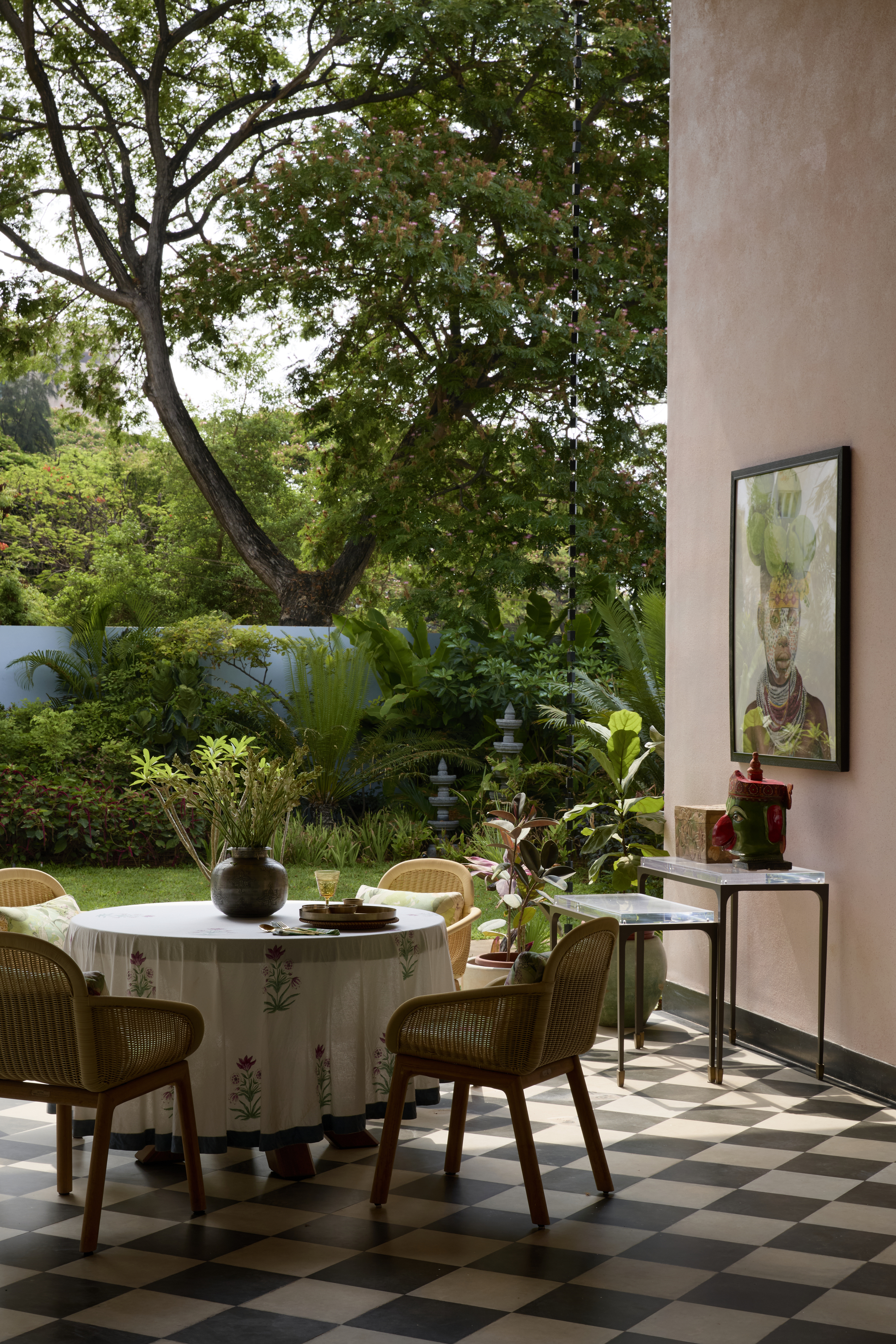 An outdoor space with chequerboard flooring, seating, a dining table with views of the tall trees