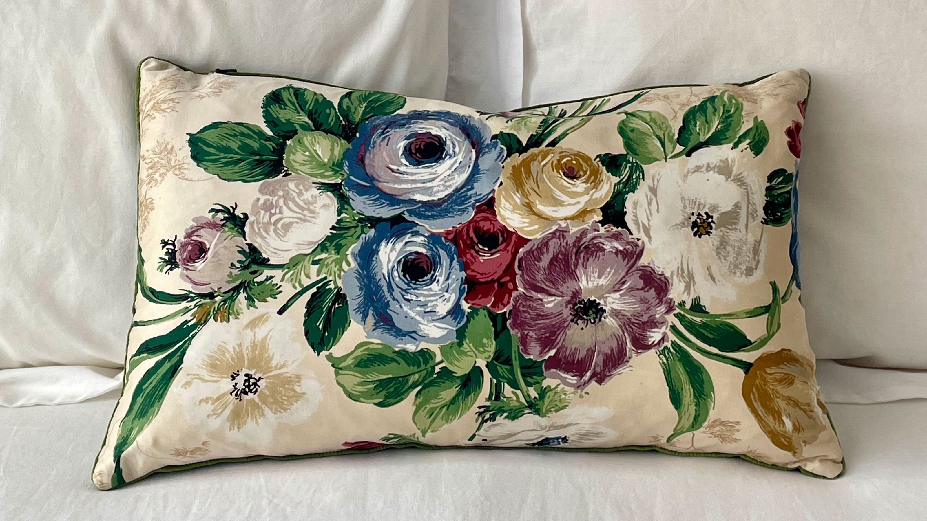 Floral print cushion sitting on bed with white linens