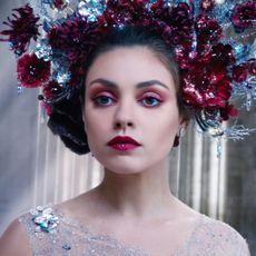 mila kunis in red makeup with a giant flower crown in a still from the movie jupiter ascending