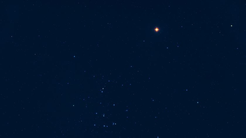 An image of the night sky showing Mars as a red star-light object close ot a number of blue-white stars against a dark blue sky.