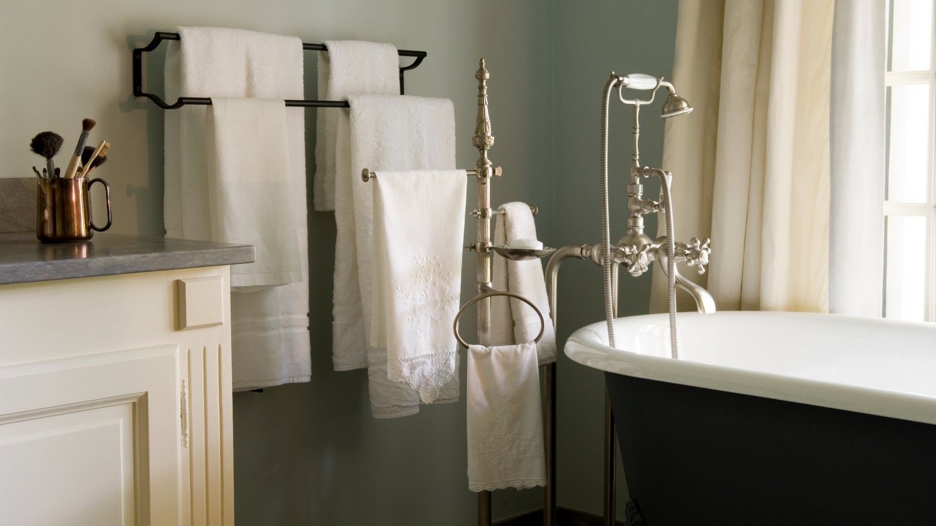 modern bathroom with freestanding tub, a large towel tail and a large vanity with make-up brushes on top