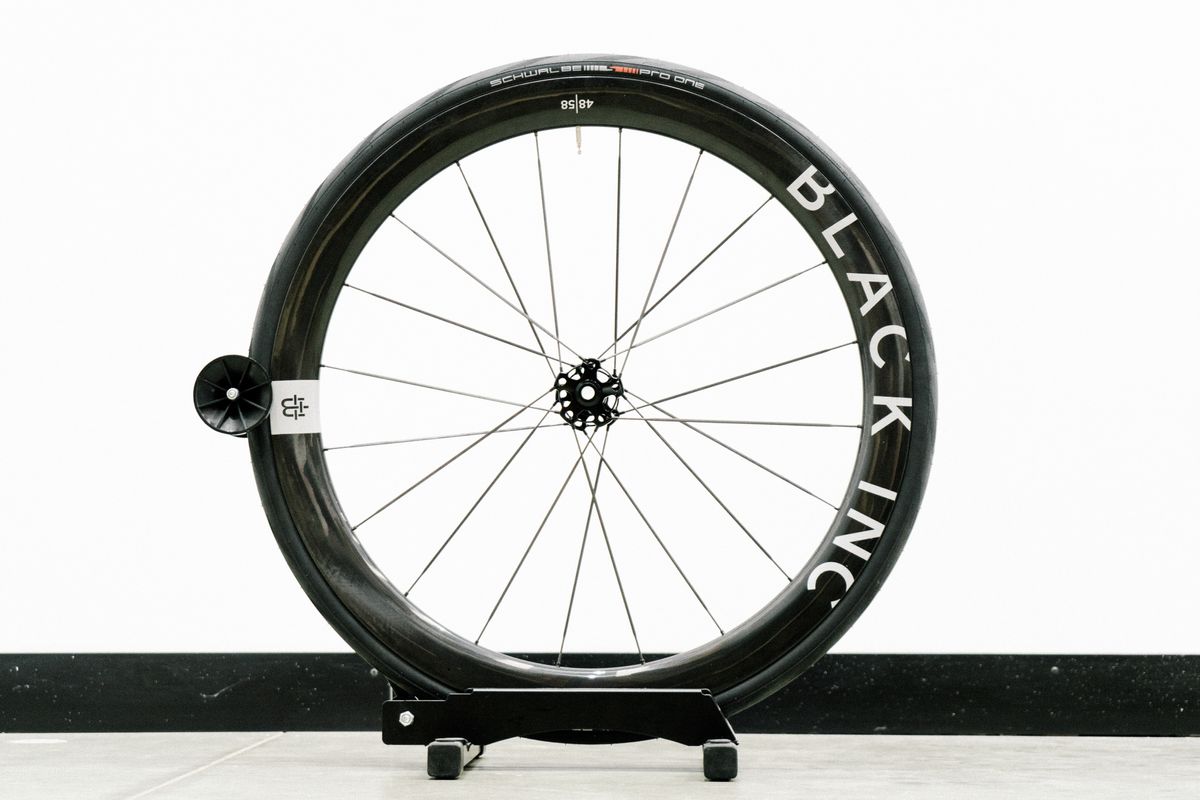 An aero road wheel stands against a white wall