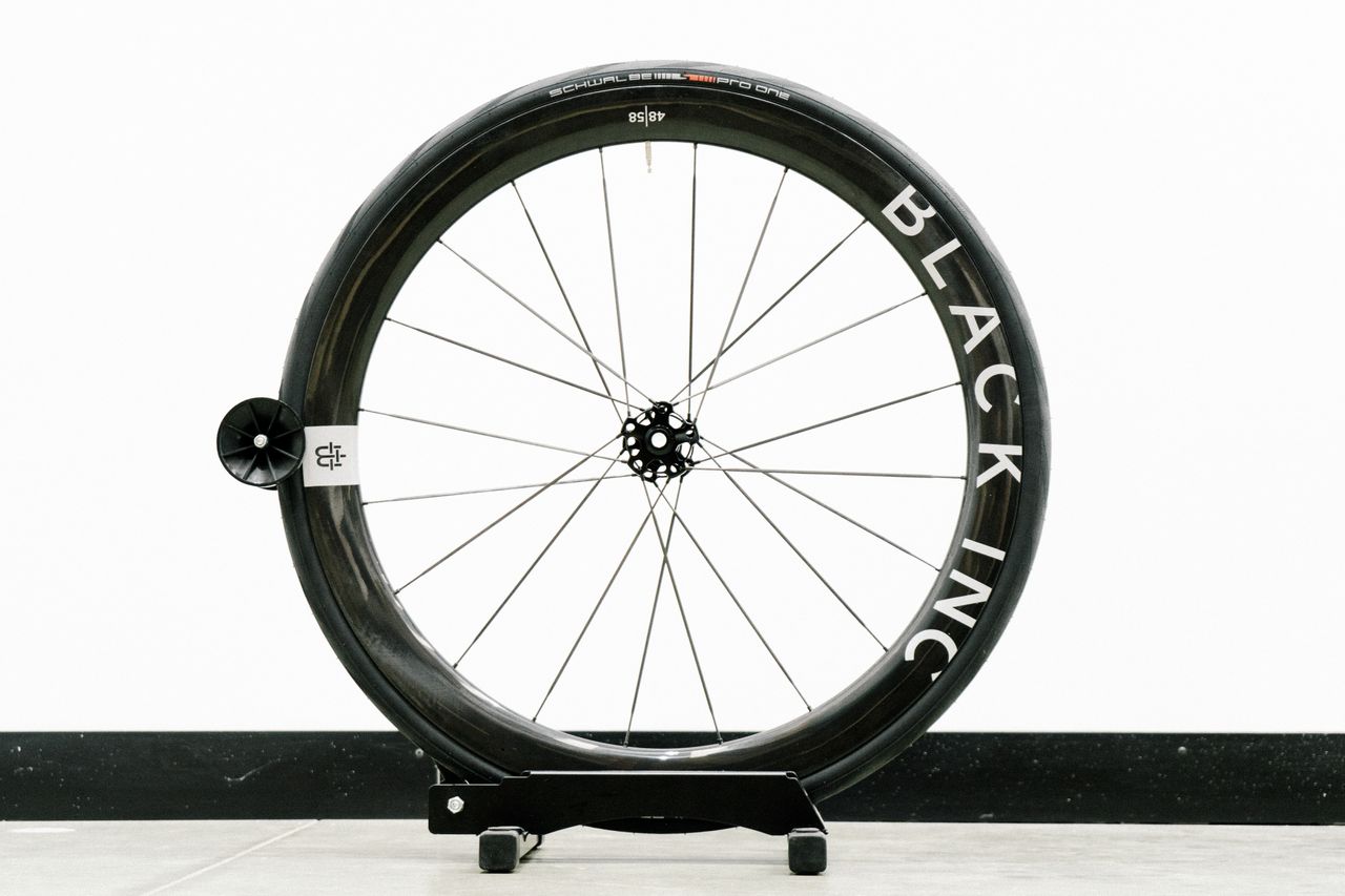 An aero road wheel stands against a white wall