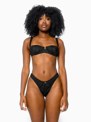 seorang model mengenakan atasan bikini balconette hitam dengan bawahan yang serasi