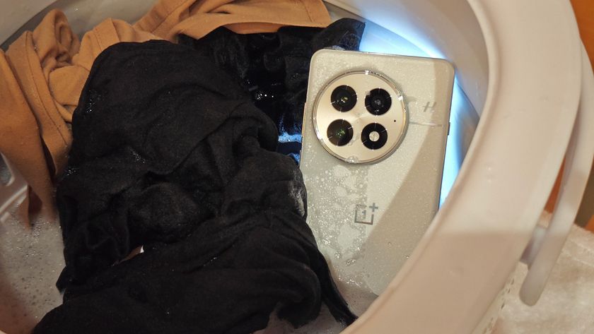 The IP69 certified white OnePlus 13 in a washing machine with clothes