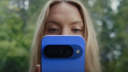 A woman looking at a blue Google Pixel 10 phone