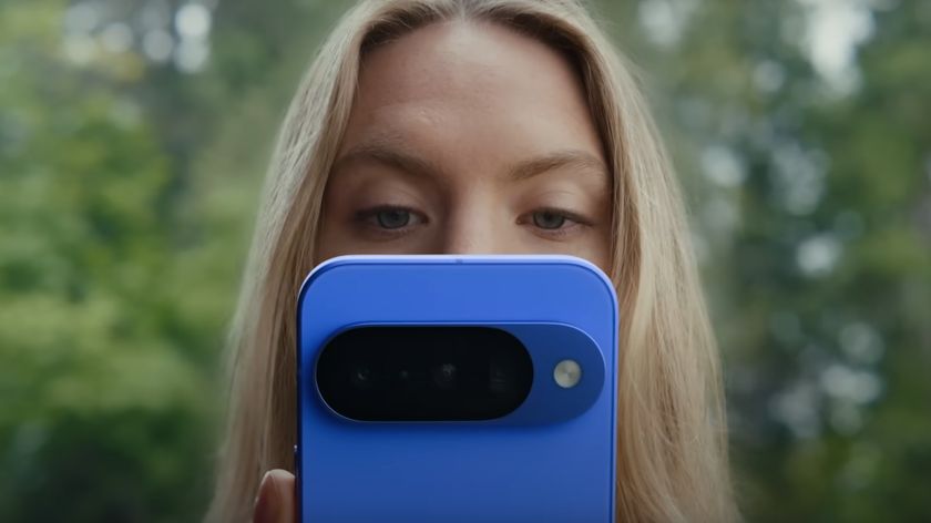 A woman looking at a blue Google Pixel 10 phone