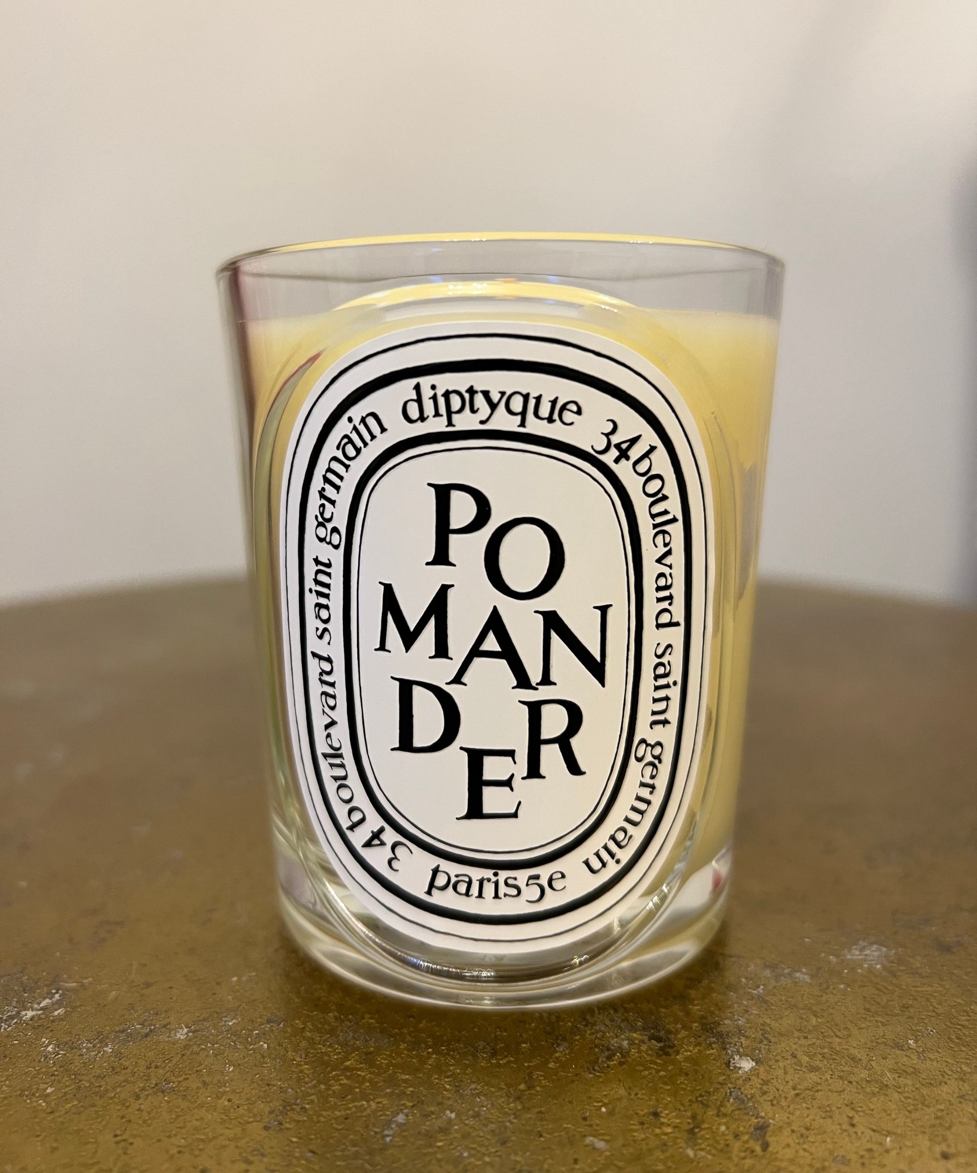 Diptyque Pomander candle on a gold table with a blurred white background