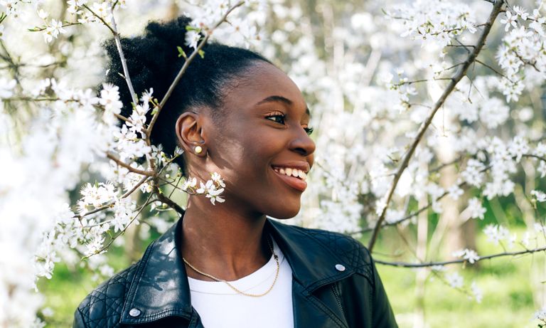 Beautiful young black girl smiling against blossom spring trees, when is the spring equinox, spring equinox 2022