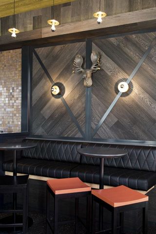 The interior features metal wine racks, distressed charcoal timber, copper and brass detailing, stitched leather seating and exposed brickwork.